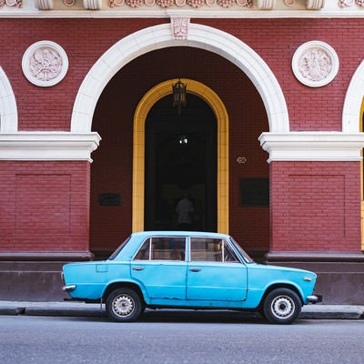 建物の前に駐車中の青い車（キューバ）の写真