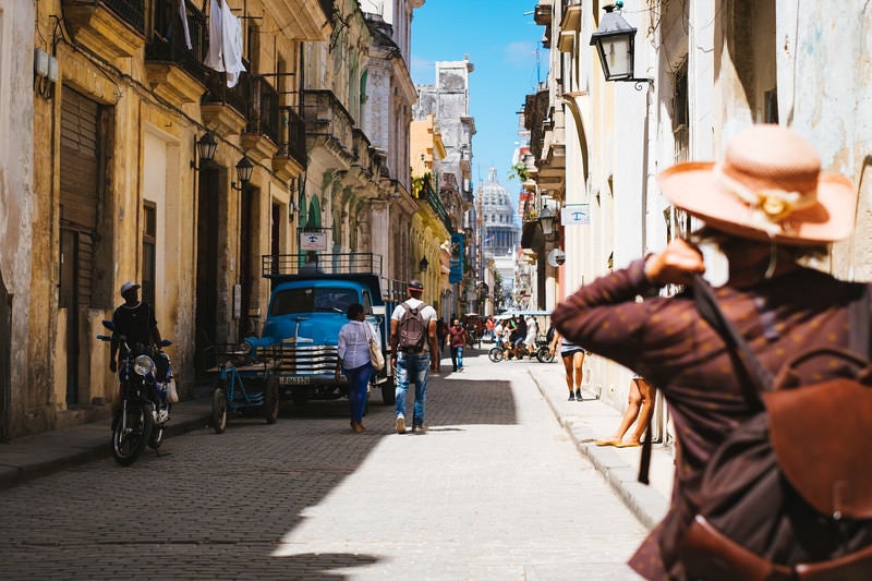 街を詮索する旅人とキューバの街並みの写真