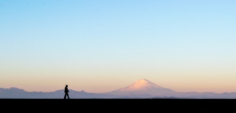 富士山をバックに散歩する男性のシルエットの写真