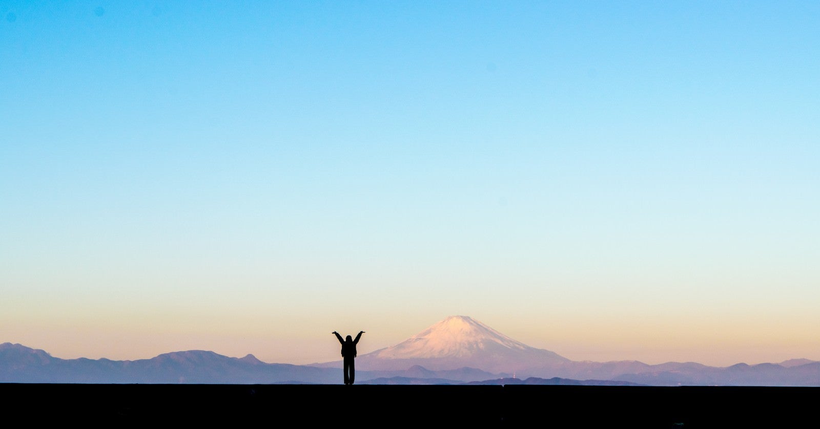 「新年！富士山をバックに両手をあげる女性のシルエット」の写真