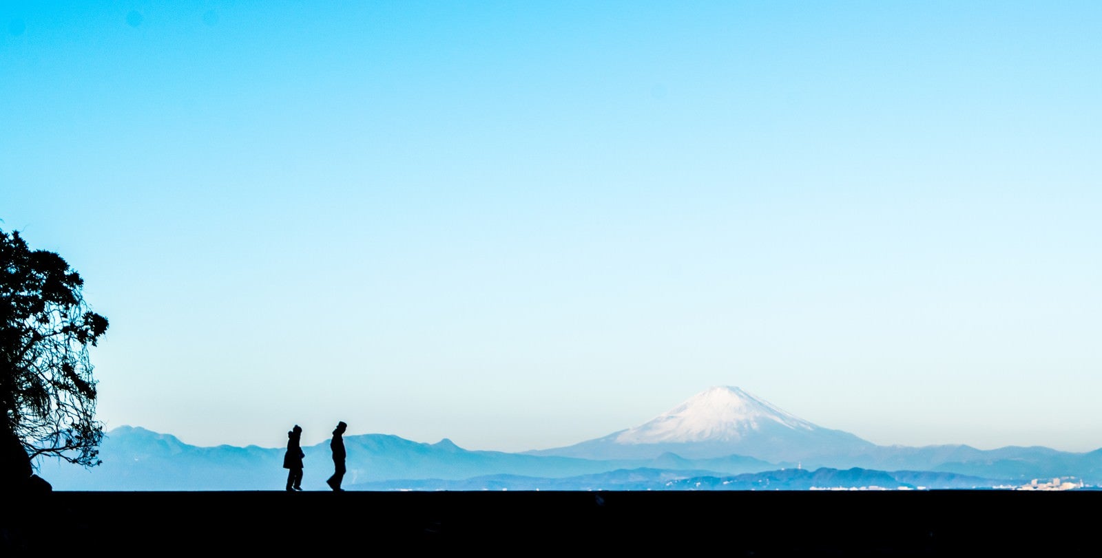 「富士山をバックに散歩する二人の男女（シルエット）」の写真