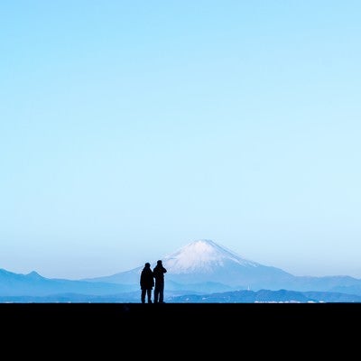 カップルで快晴の富士山を見ているシルエットの写真