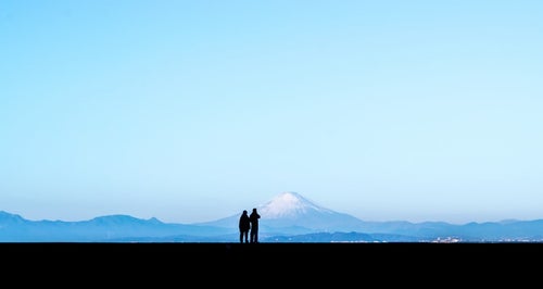 カップルで快晴の富士山を見ているシルエットの写真