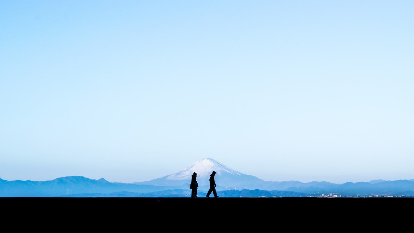 「富士山を見ながら散歩する恋人のシルエット」の写真