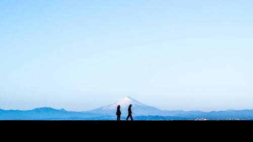 富士山を見ながら散歩する恋人のシルエットの写真