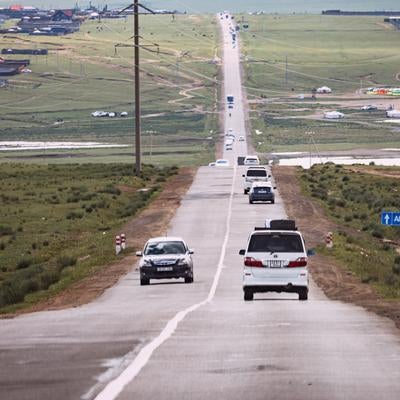 モンゴルの草原を貫く長い道路と集落の写真