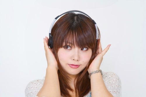 ヘッドフォンを耳に当てる女性の写真