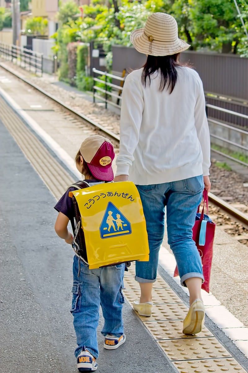 「駅のホームを歩く親子」の写真