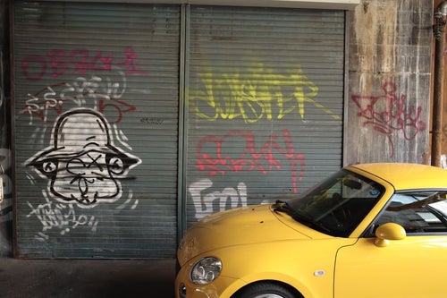 黄色い車とシャッターの落書きの写真