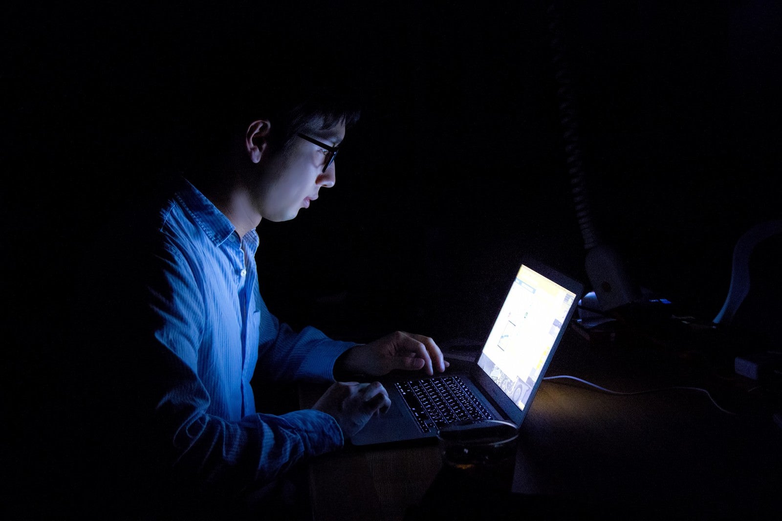 「暗闇でPCを使う残業中の男性」の写真［モデル：大川竜弥］