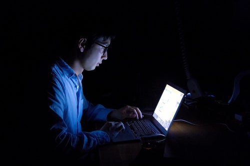 暗闇でPCを使う残業中の男性の写真