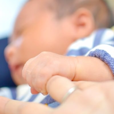 母親の指を握る赤ちゃんの写真