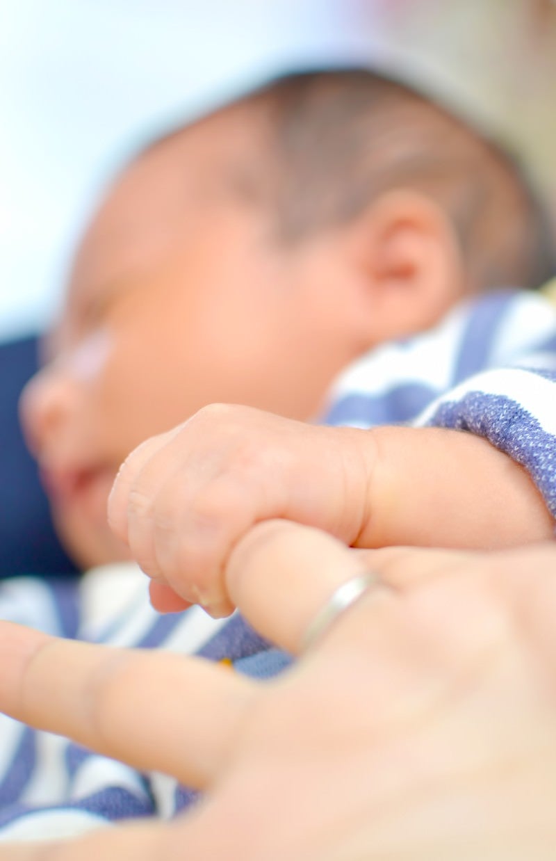 「母親の指を握る赤ちゃん」の写真