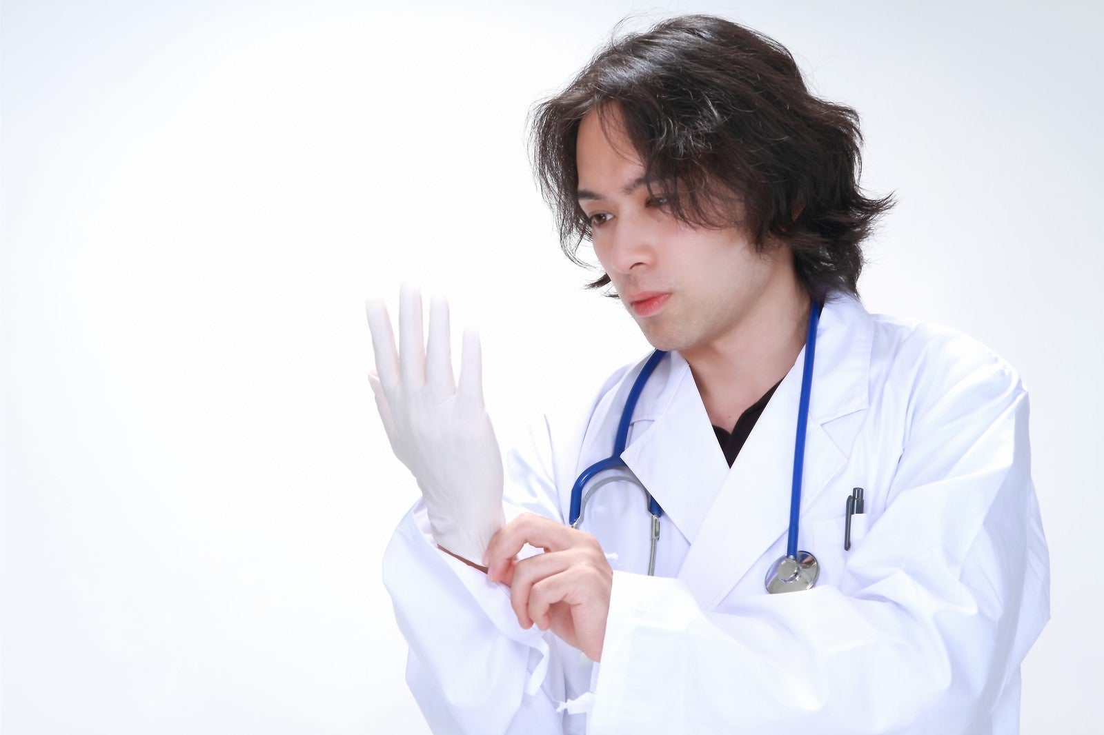 「ゴム手袋を装着する若い医師」の写真［モデル：マイケルリュー］