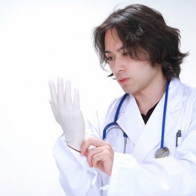 ゴム手袋を装着する若い医師の写真