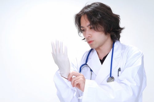 ゴム手袋を装着する若い医師の写真