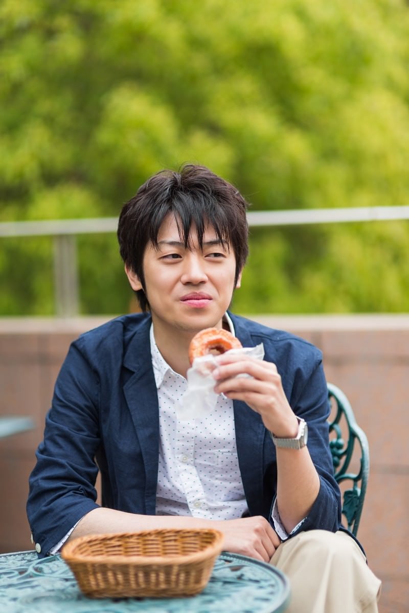 「テーブルでドーナツを食べる男性」の写真［モデル：Tsuyoshi.］