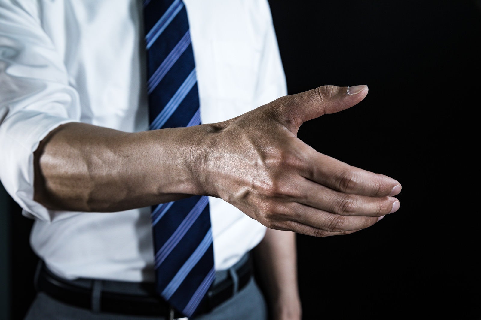 「腕まくりして血管を強調した上で握手を求める会社員」の写真［モデル：大川竜弥］