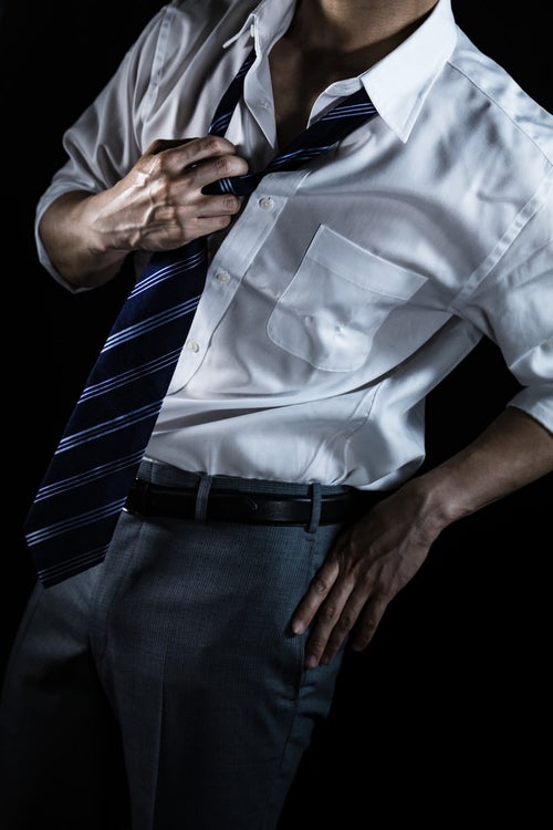 ネクタイを緩めるスーツ姿の男性（クールビズ）の写真