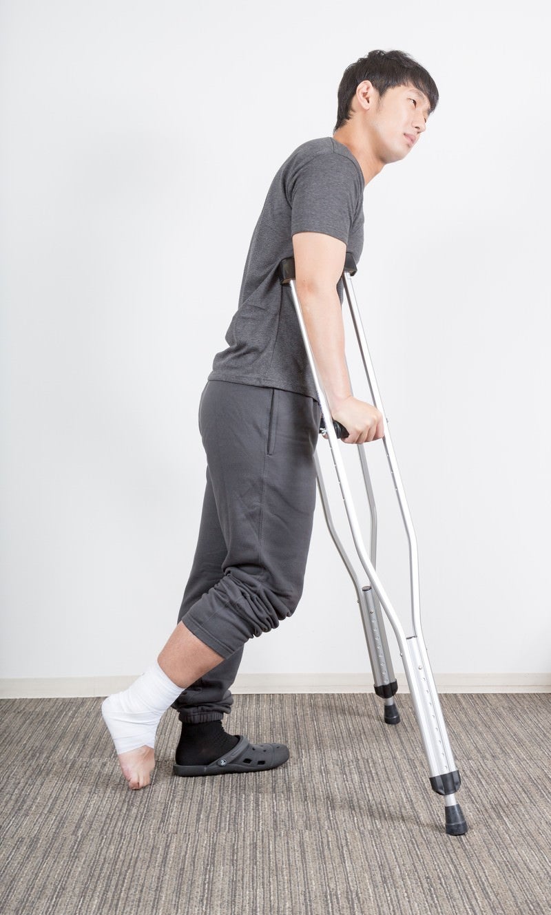 「右足を捻挫して松葉杖の男性」の写真［モデル：大川竜弥］