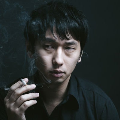 暗い喫煙室で煙草を吸う男性の写真