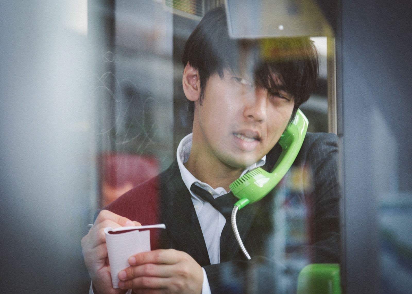 「電話ボックスのピンクチラシが気になるブン屋」の写真［モデル：大川竜弥］