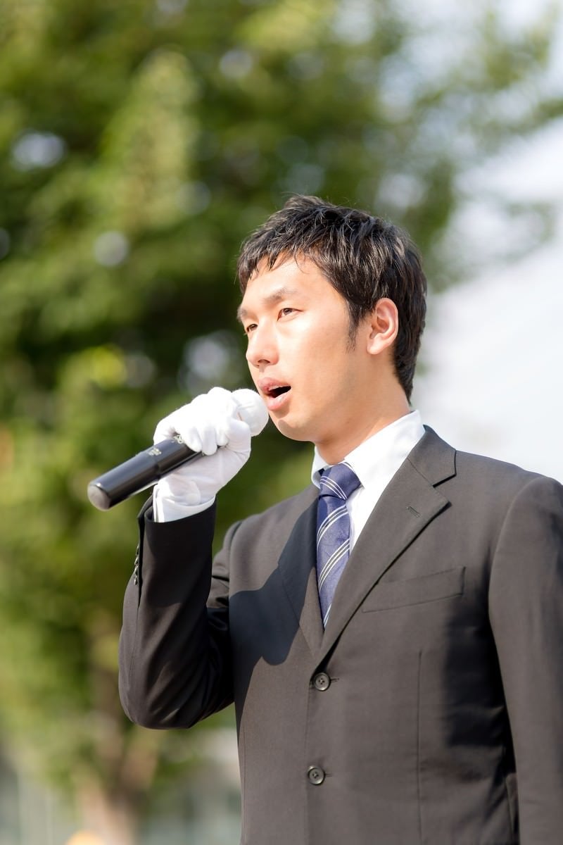 「街灯演説するマイクを持った若い立候補者」の写真［モデル：大川竜弥］