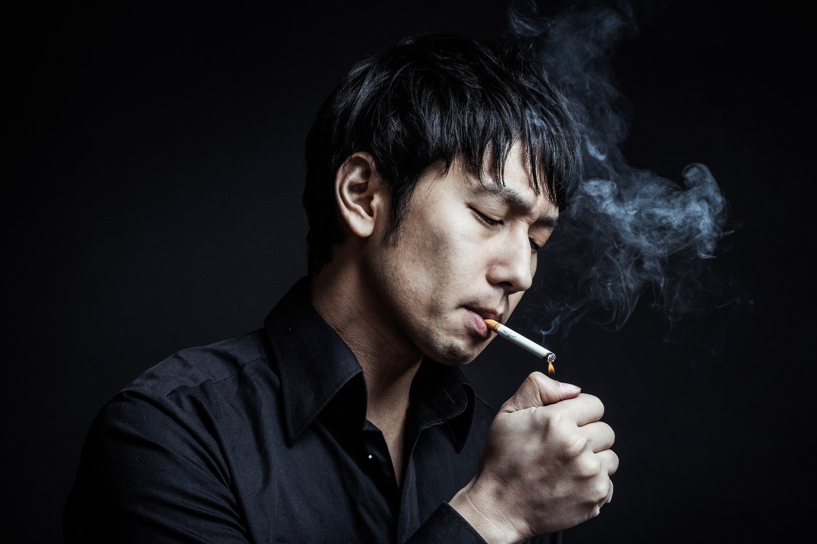 「指先でタバコに火をつける新進気鋭のマジシャン」の写真［モデル：大川竜弥］
