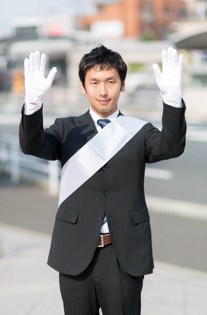「両手をあげて支援を呼びかける党公認候補」の写真［モデル：大川竜弥］