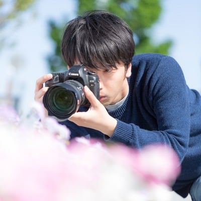 一眼レフで花を接写するカメラマンの写真