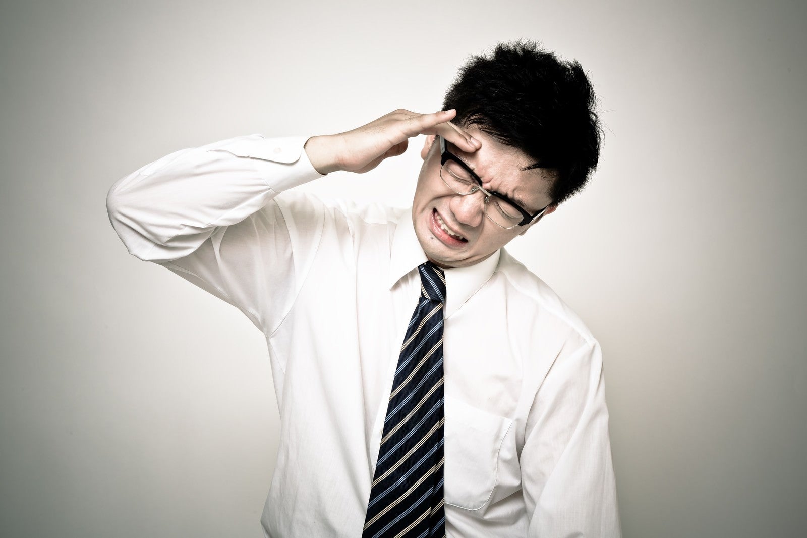 「頭が割れるように痛い会社員の男性」の写真［モデル：OZPA］