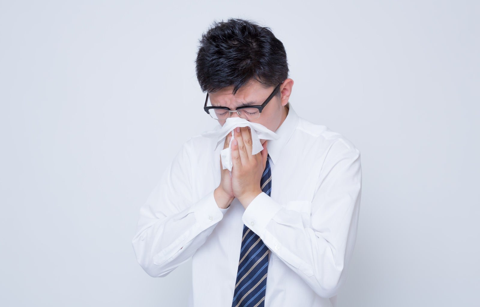「花粉症で鼻をかむ男性」の写真［モデル：OZPA］