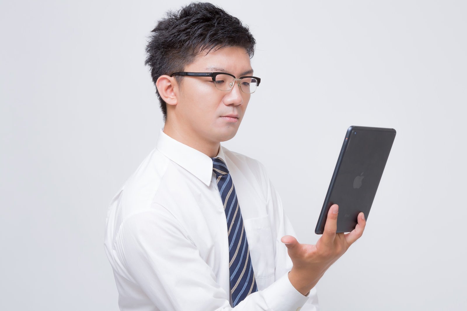 「iPad mini で電子書籍を読むビジネスマン」の写真［モデル：OZPA］