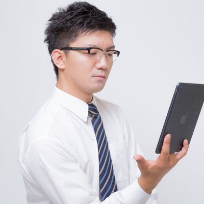 iPad mini で電子書籍を読むビジネスマンの写真