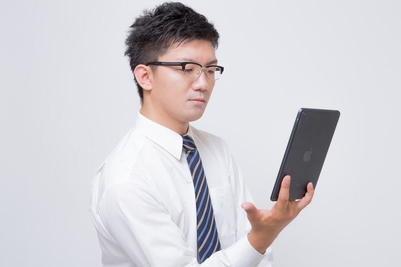 iPad mini で電子書籍を読むビジネスマンの写真