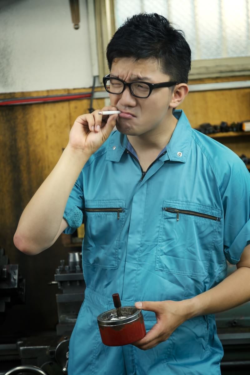 「工場で煙草を吸う男性」の写真［モデル：OZPA］