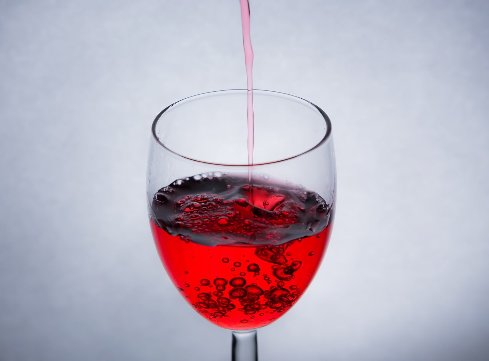 「グラスに赤い液体を注ぐ」の写真