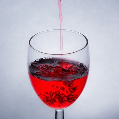 グラスに赤い液体を注ぐの写真