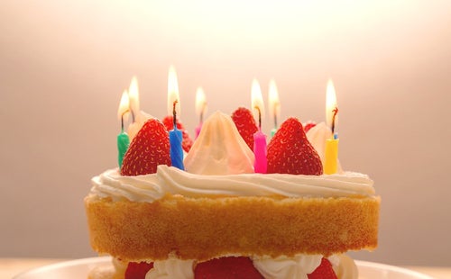 ケーキのロウソクに火をつけて「おめでとう」の写真