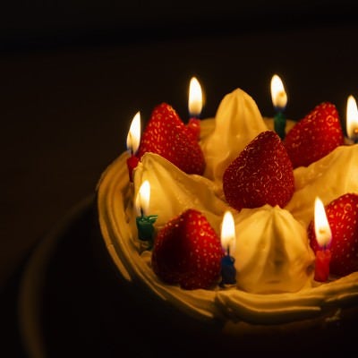 ロウソクの明かりとイチゴのケーキの写真