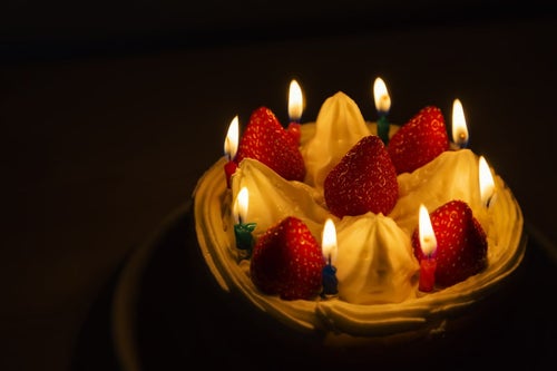 ロウソクの明かりとイチゴのケーキの写真