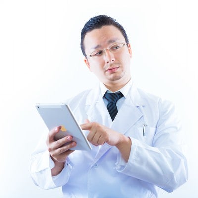 タブレットを持って検索をする白衣のドクターの写真