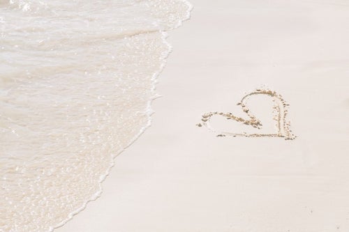 ハートが描かれた砂浜と波の写真