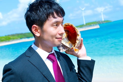 南の島で貝フォンを使用するビジネスマンの写真