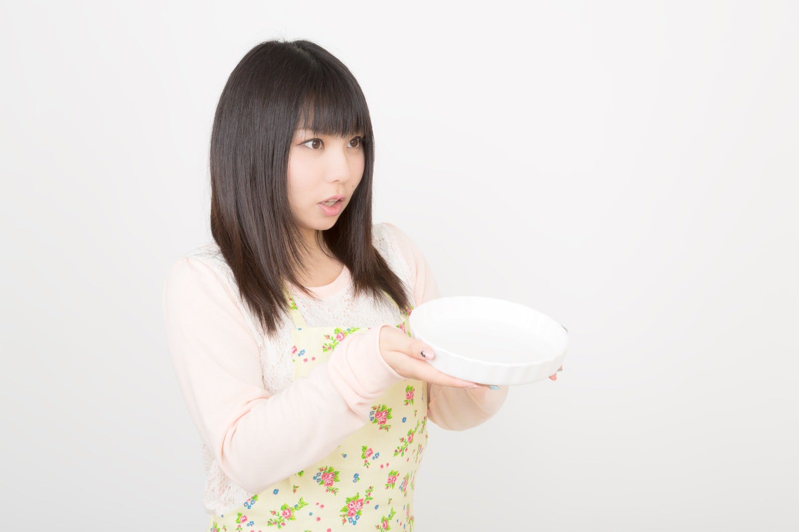 「大きなお皿を両手で持ったエプロン姿の女性」の写真［モデル：Lala］