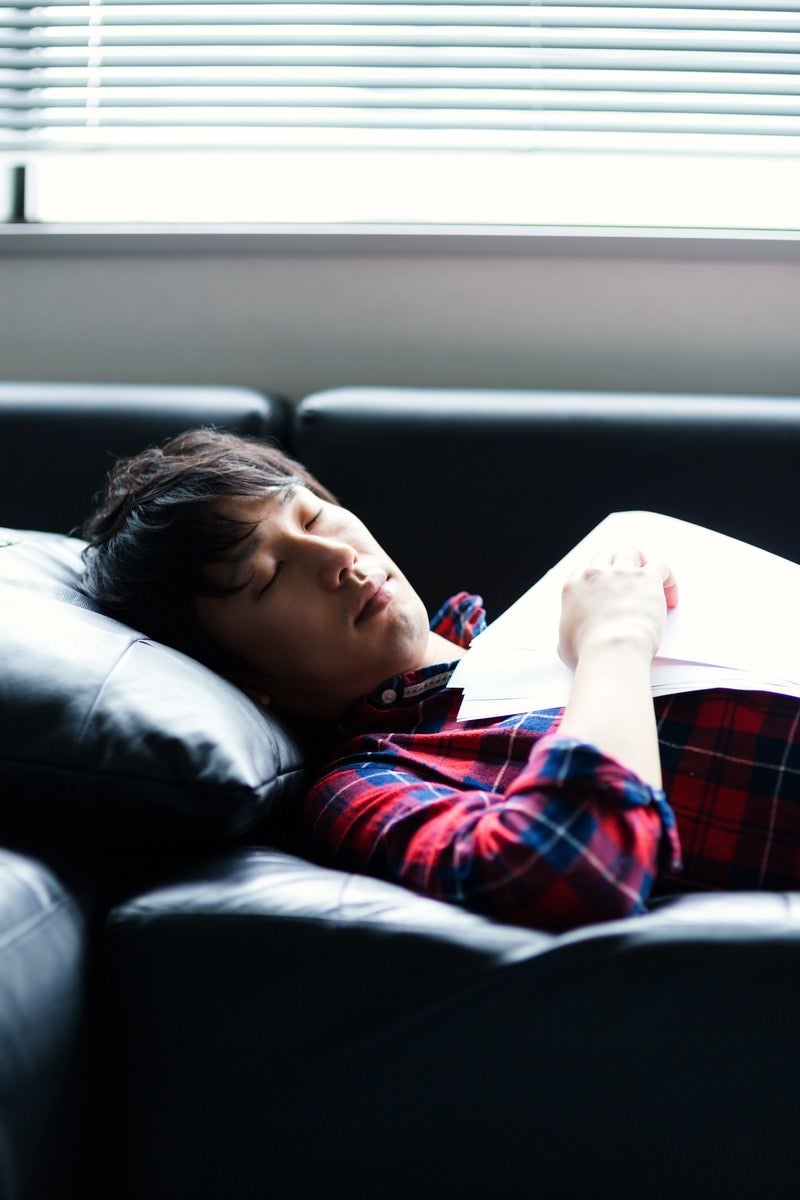 「資料を持ちながら寝落ちする男性」の写真［モデル：大川竜弥］