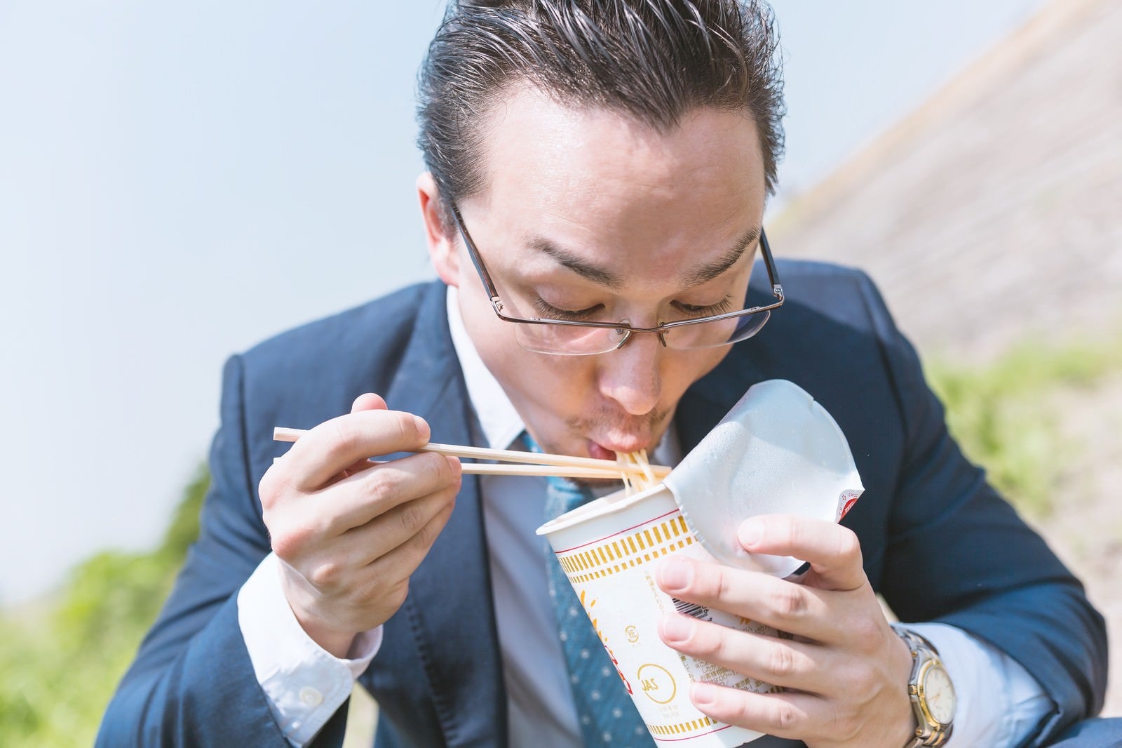 「カップラーメンをすすり食らうビジネスマン（ドイツ人ハーフ）」の写真［モデル：Max_Ezaki］