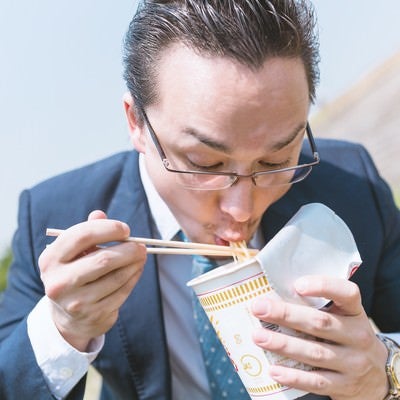 カップラーメンをすすり食らうビジネスマン（ドイツ人ハーフ）の写真
