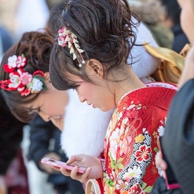 成人式の着物姿でスマートフォンをいじる女性の写真