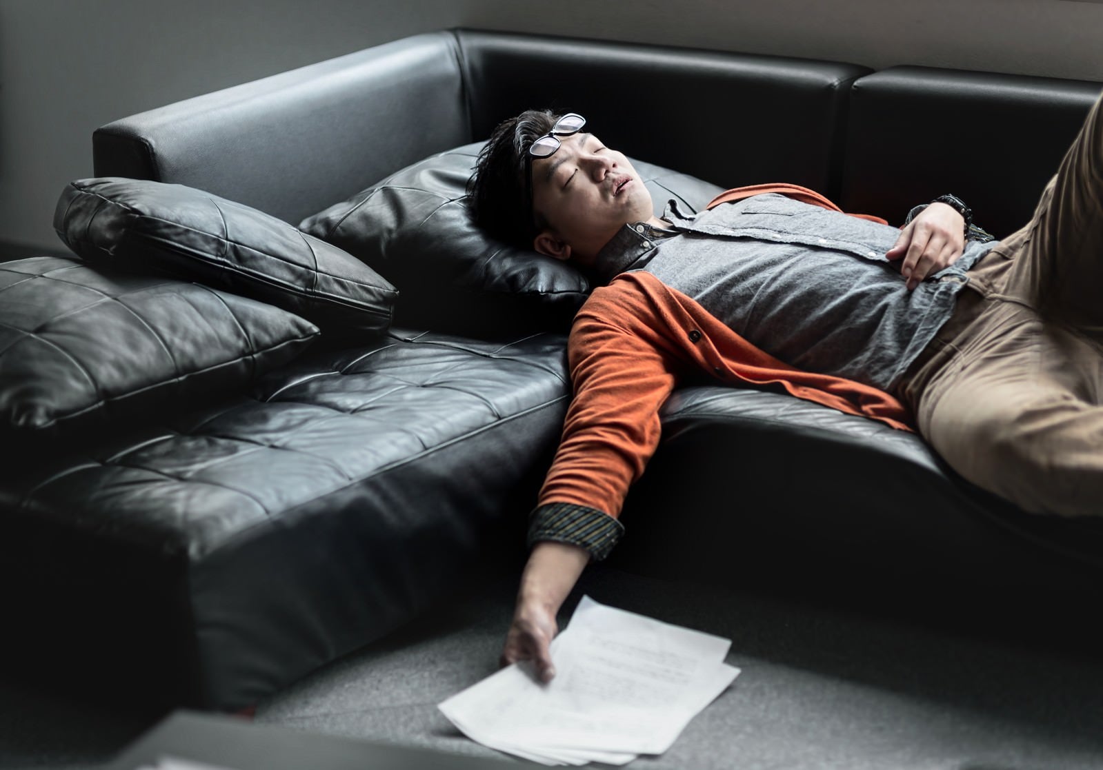 「原稿を持ってソファーで寝落ちする担当の男性」の写真［モデル：OZPA］
